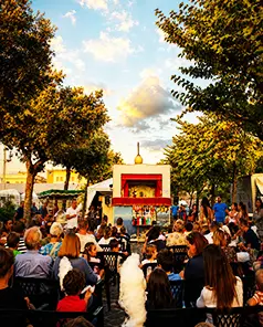 Folla di spettatori seduti in piazza durante uno spettacolo del Teatrino Mercurio